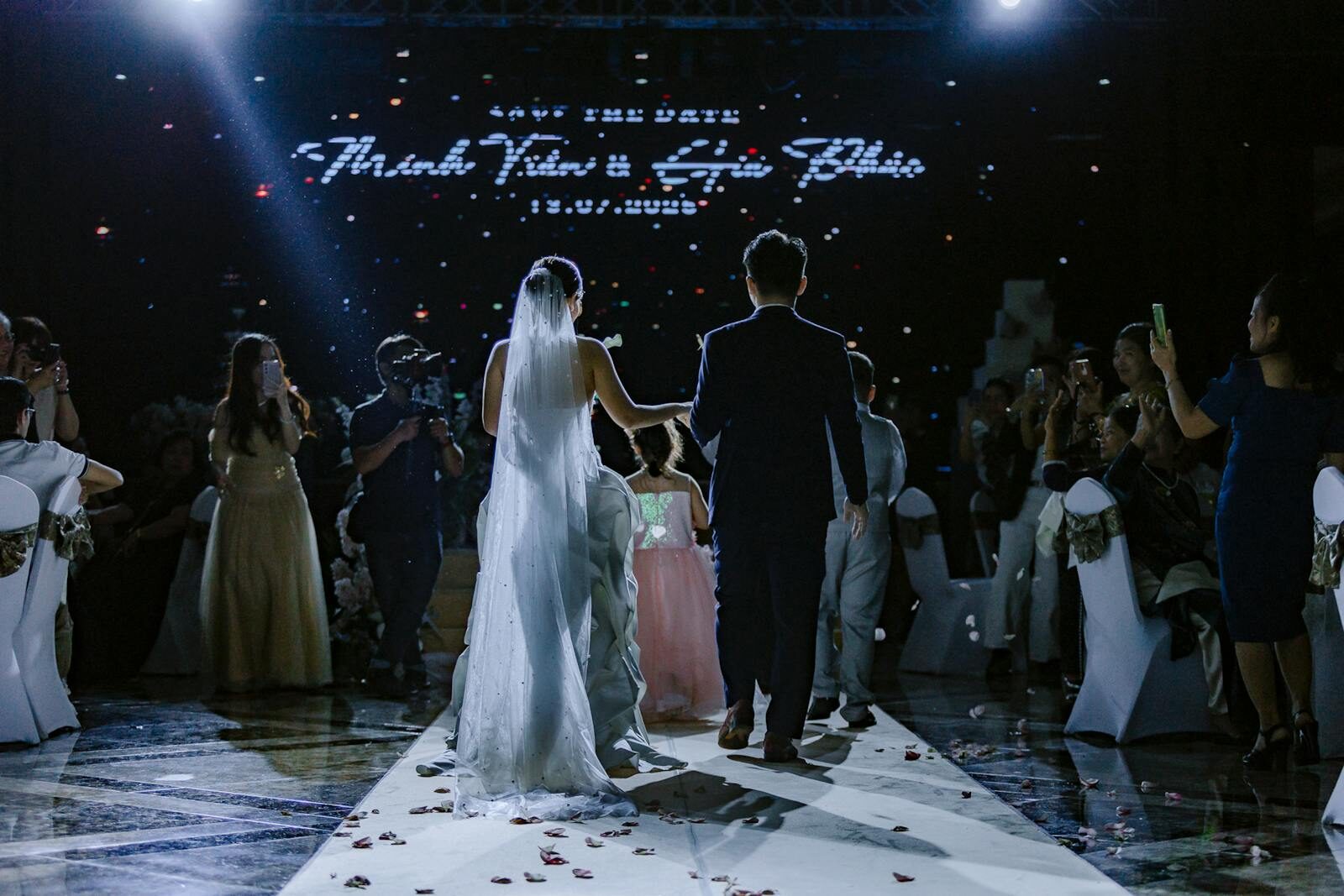Bride and groom walking down aisle at a beautiful indoor wedding ceremony with guests watching.