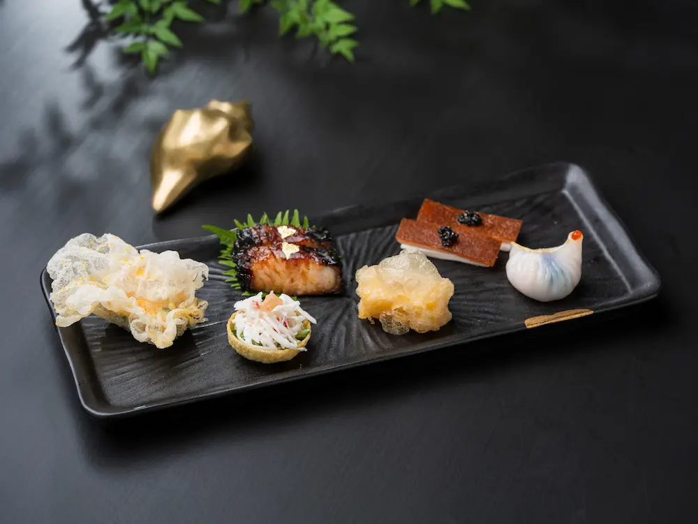 前菜六品匯聚山珍海味，包括「金陵脆皮乳豬、醞火烏金叉燒、金沙北海道元貝、椒鹽松茸戈渣、藤香帝王蟹、瑤柱蛋